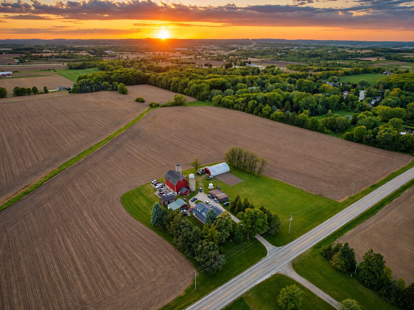 Aerial of a Wisconsin farm with a red barn and silo at sunset