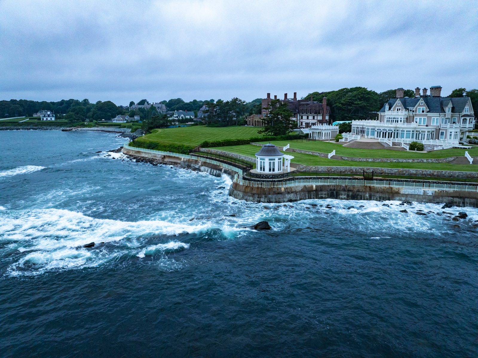 Aerial of an oceanfront estate, lawn and seawall at dusk