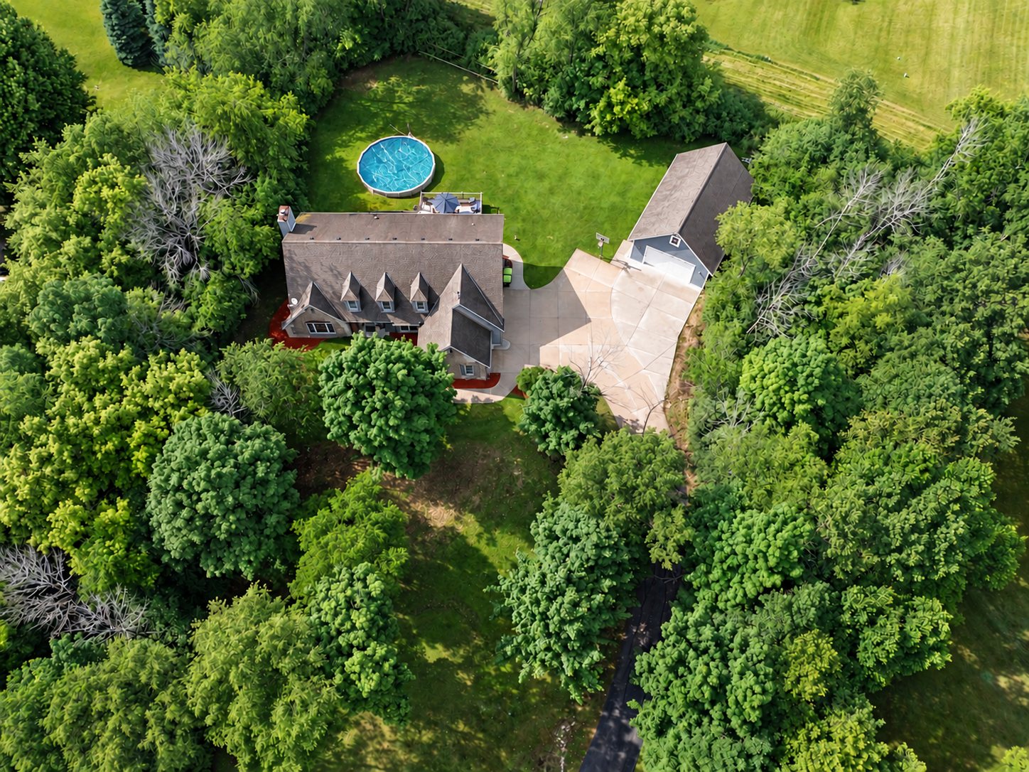 Top-down drone photo of a country home with a pool and detached garage, for a real estate listing in Wisconsin