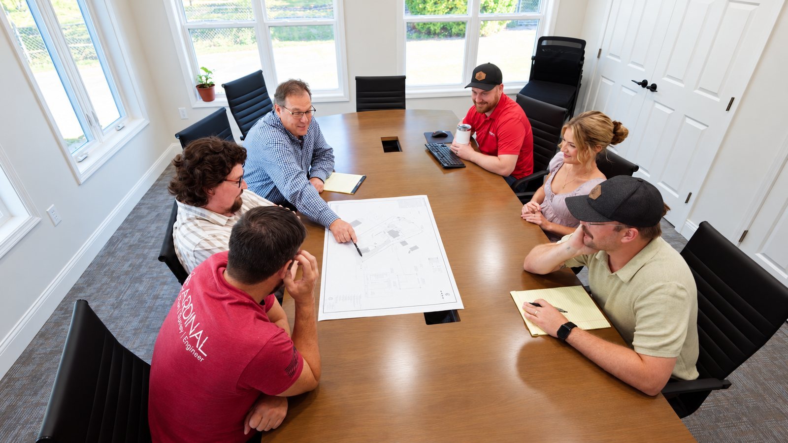 Engineering team collaborating around a blueprint on a conference table