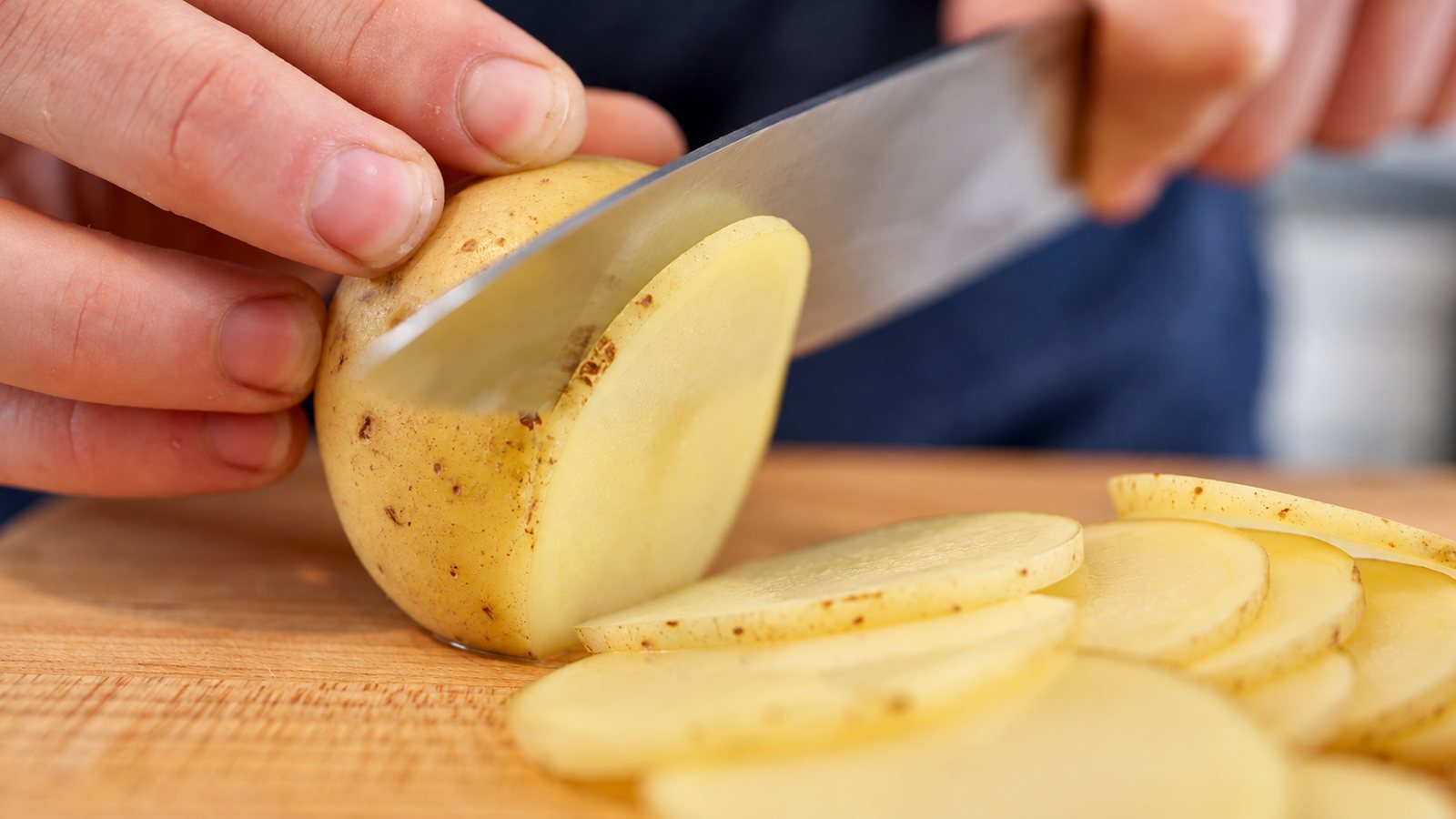 Hands slicing a potato, close-up from a food brand video